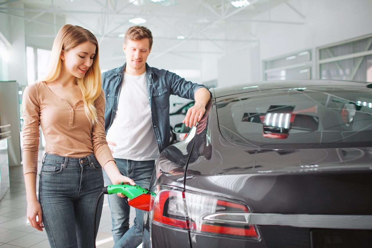 Mann und Frau stehen neben einem Auto und betanken es