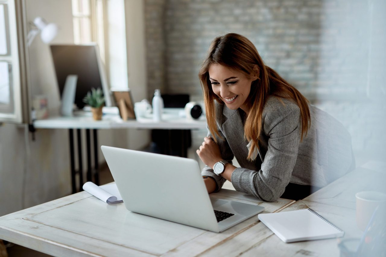 Young,Happy,Businesswoman,Reading,An,E-mail,While,Working,In,The