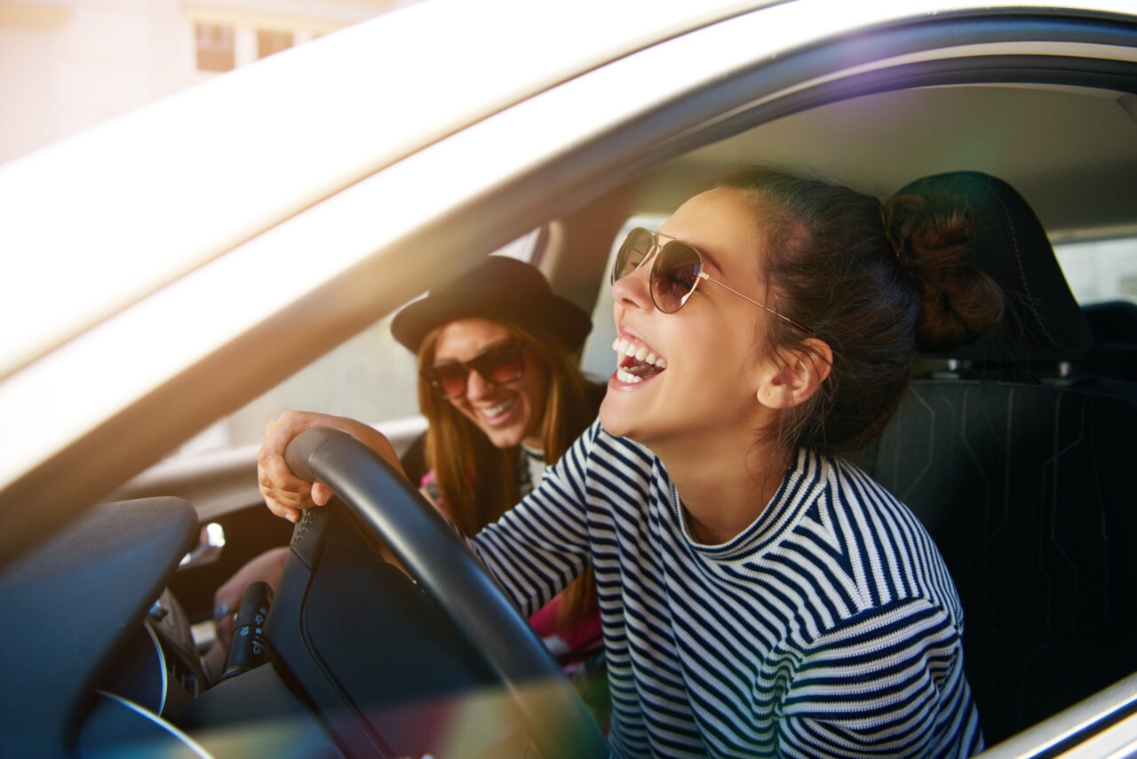 Fuhrparkmanagement: Ein schönes Paar sitzt mit erhobenen Händen in seinem Cabrio.