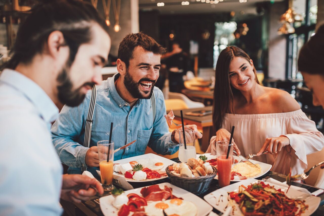 Essenszuschuss: Mitarbeiter sitzen lachend beim Essen in einem Restaurant