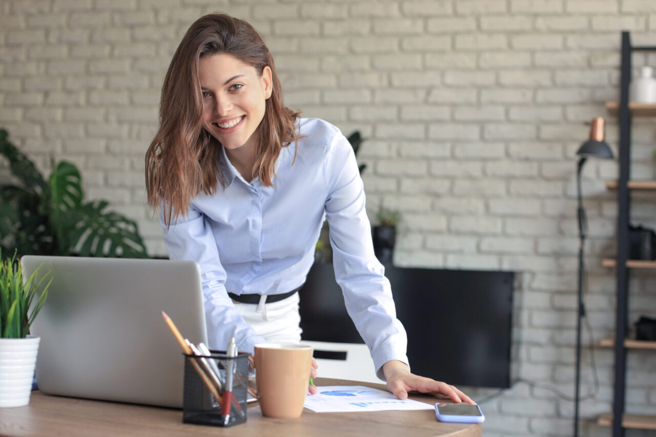 Young business woman standing in her home office writing notes.