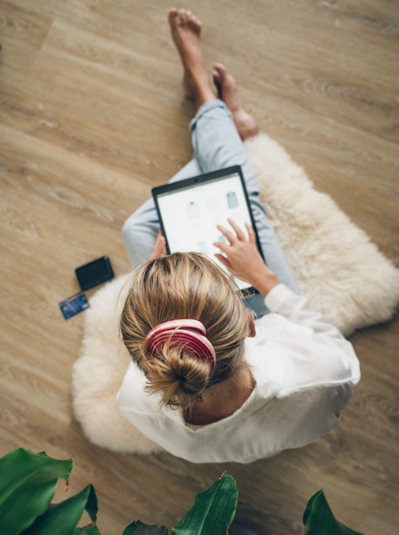 Elektronik-Leasing: Frau sitzt mit Tablet in der Hand auf Teppich